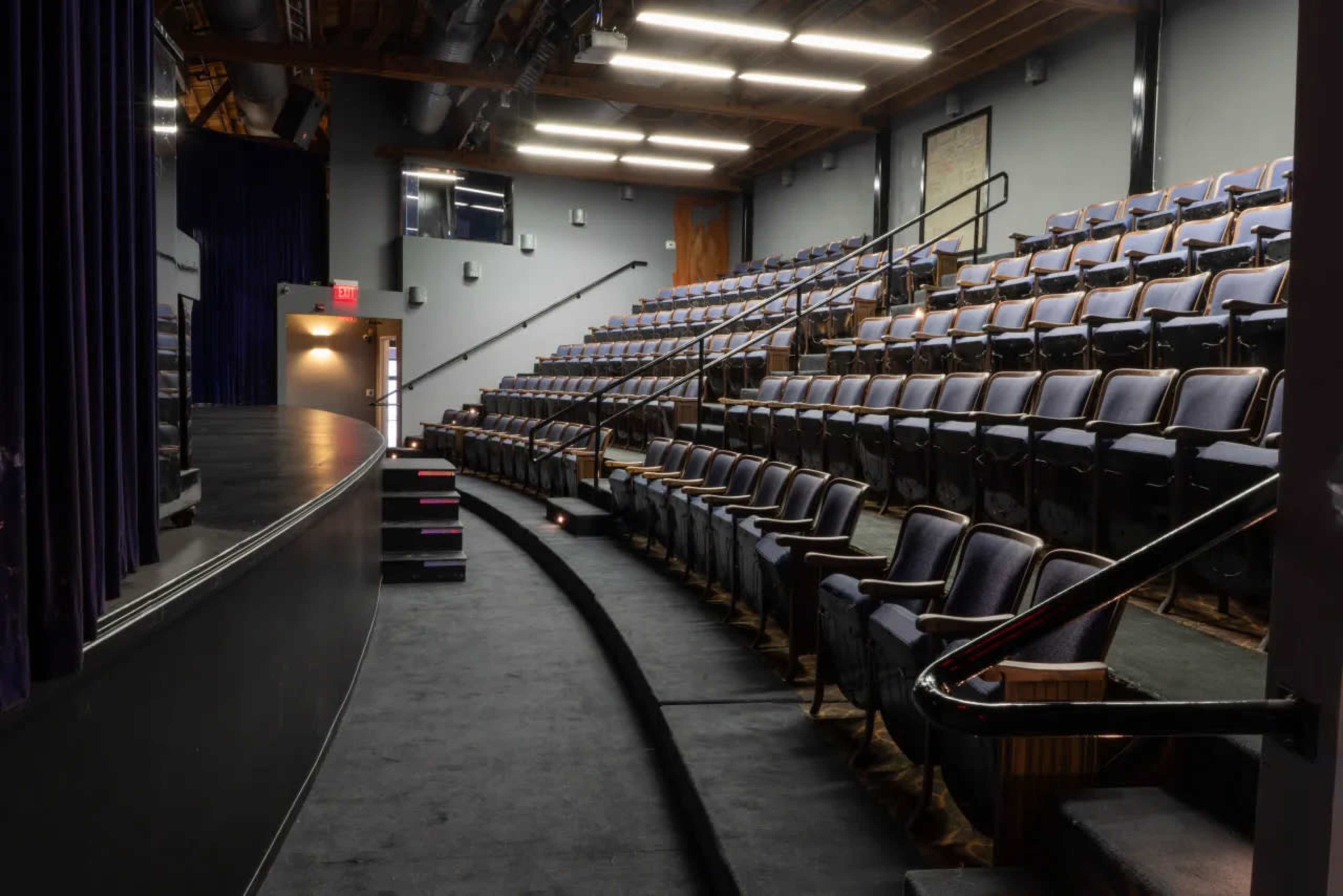 A theater interior with empty tiered seating and a curved stage.