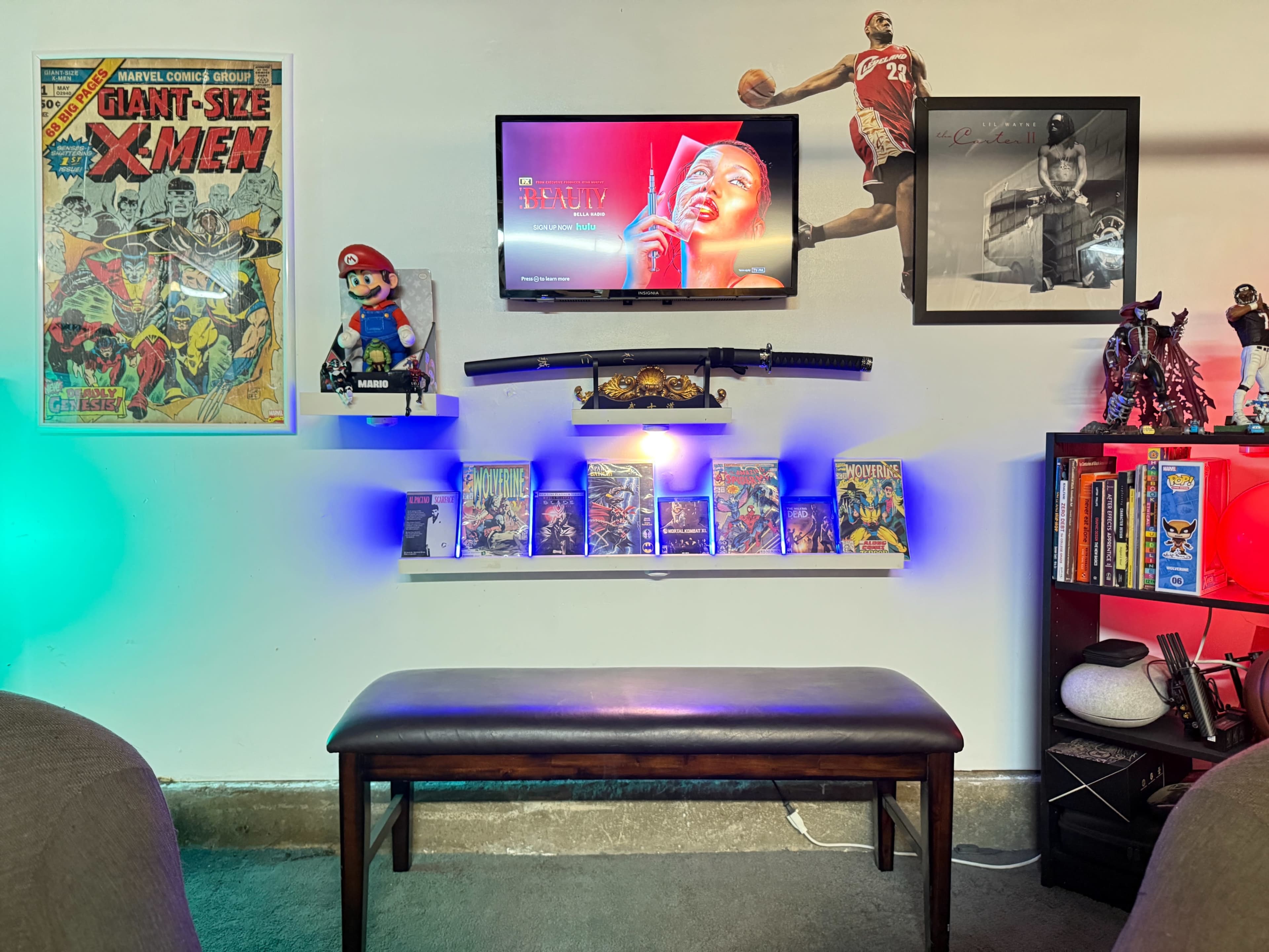 The scene features a cozy entertainment area with a wall-mounted television above a wooden bench, surrounded by comic book art, shelves of video games, and decorative figures.