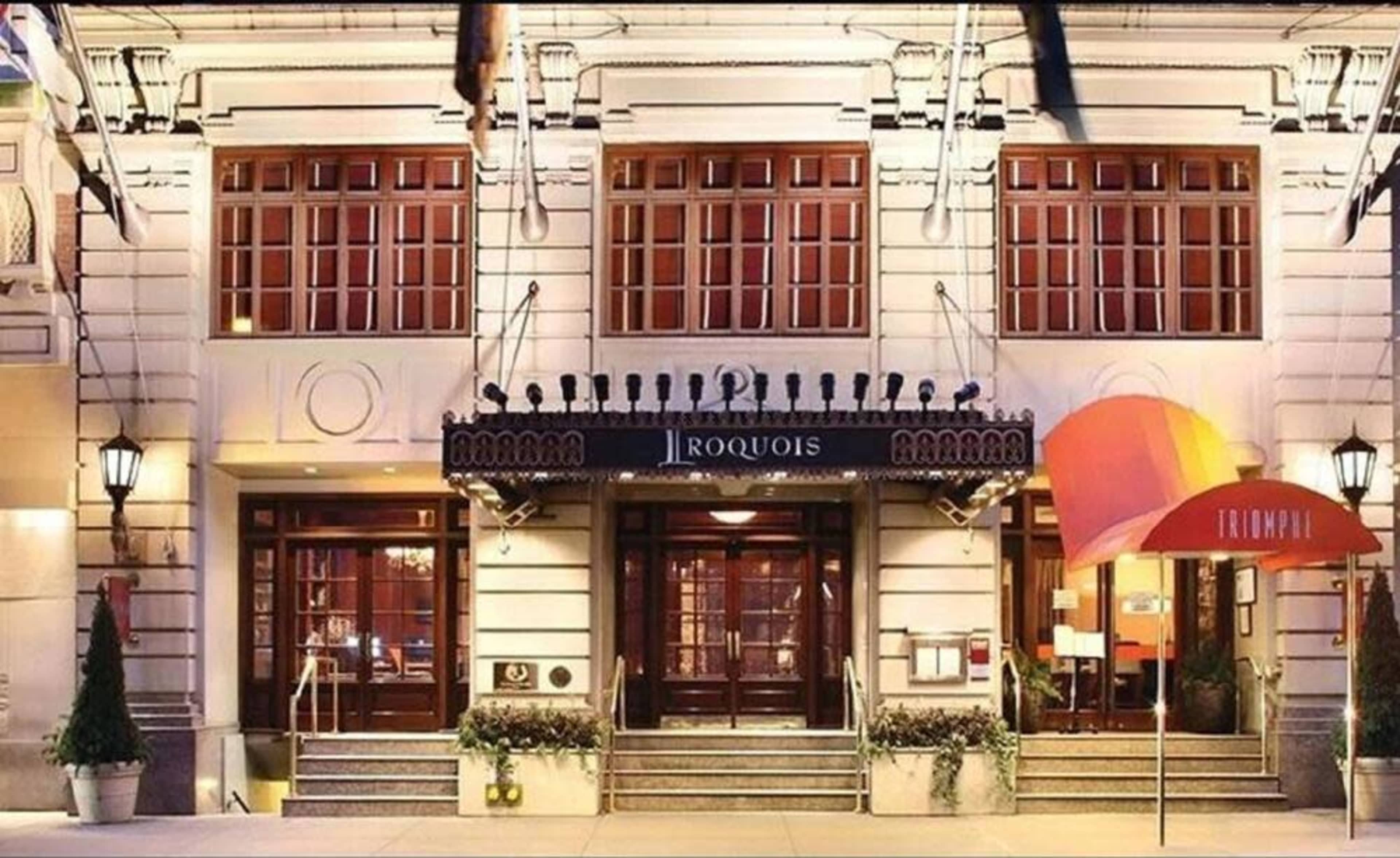 The entrance of the Iroquois Hotel, featuring large wooden doors and a canopy with the hotel's name.
