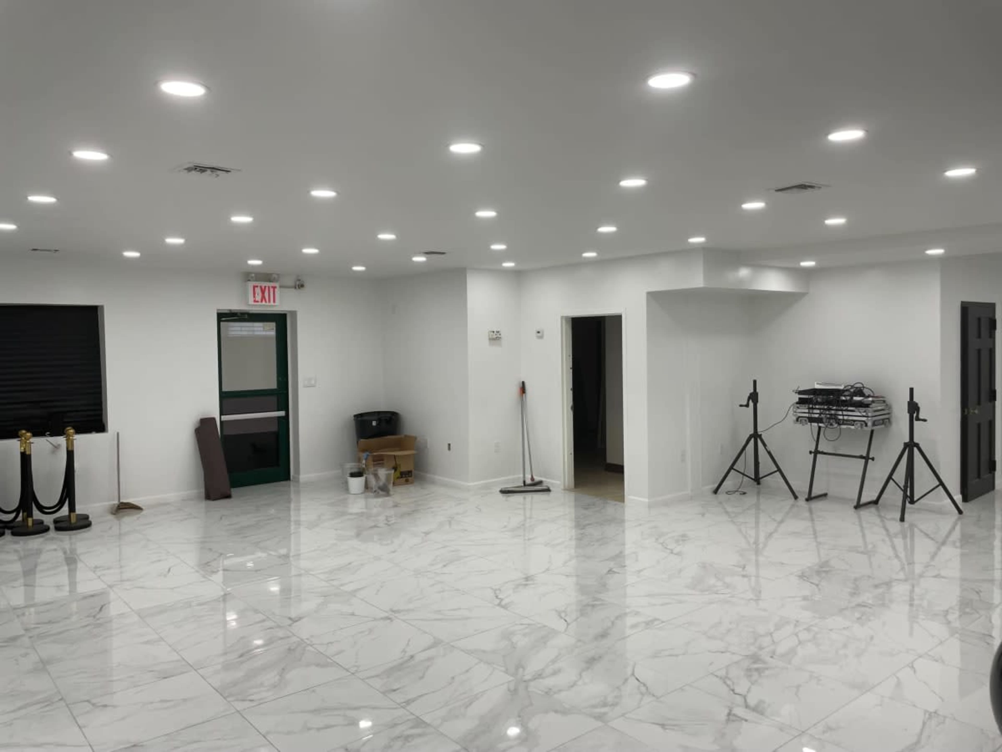 The image shows a spacious room with white walls, a glossy marble floor, and several light fixtures on the ceiling.