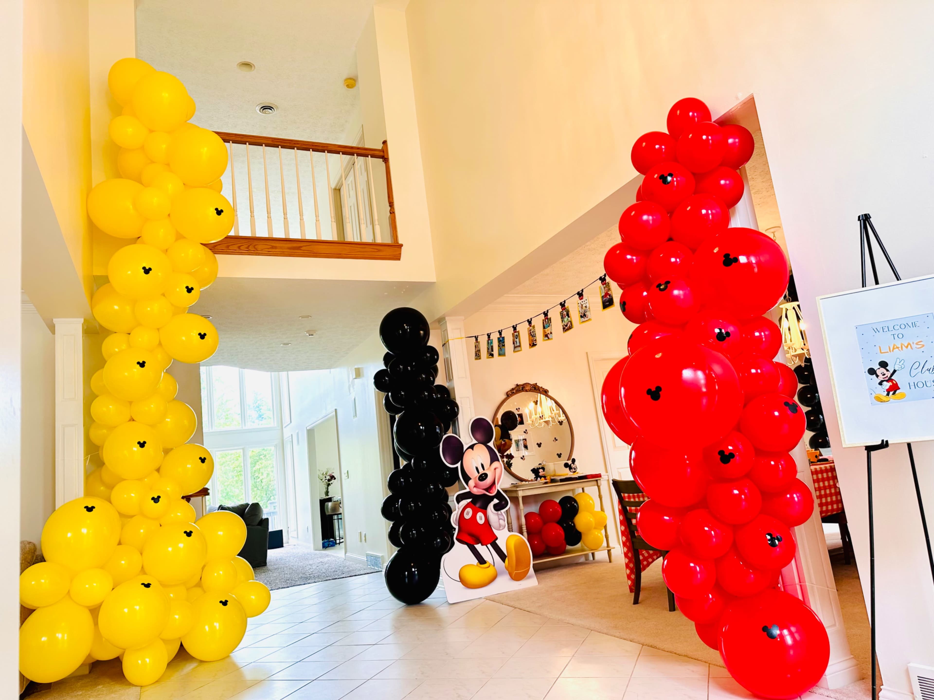 The entrance features tall balloon decorations in yellow, black, and red, with a Mickey Mouse cutout placed alongside.