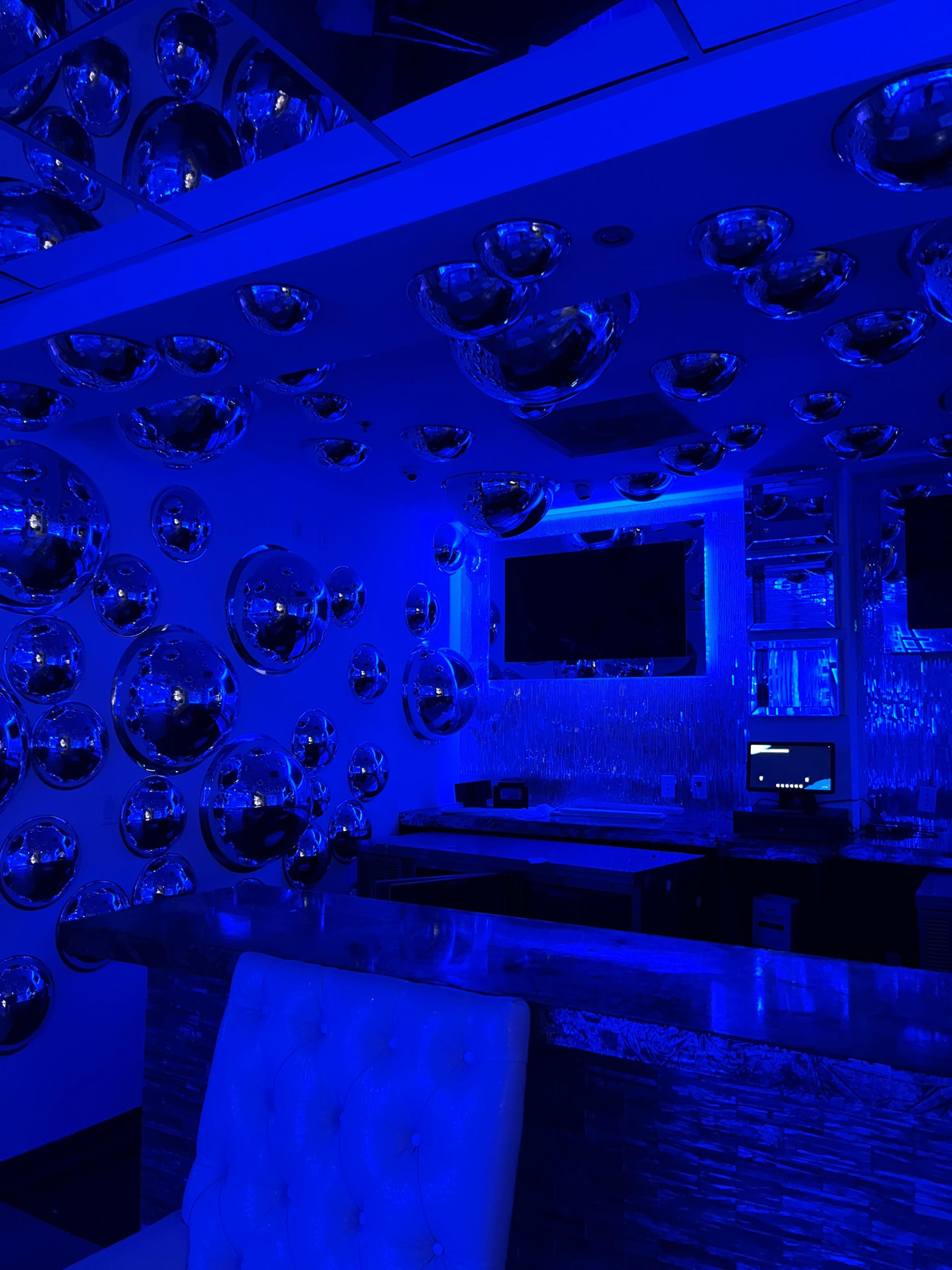 The image shows a dimly lit room with blue lighting and numerous shiny, spherical decorations on the walls.