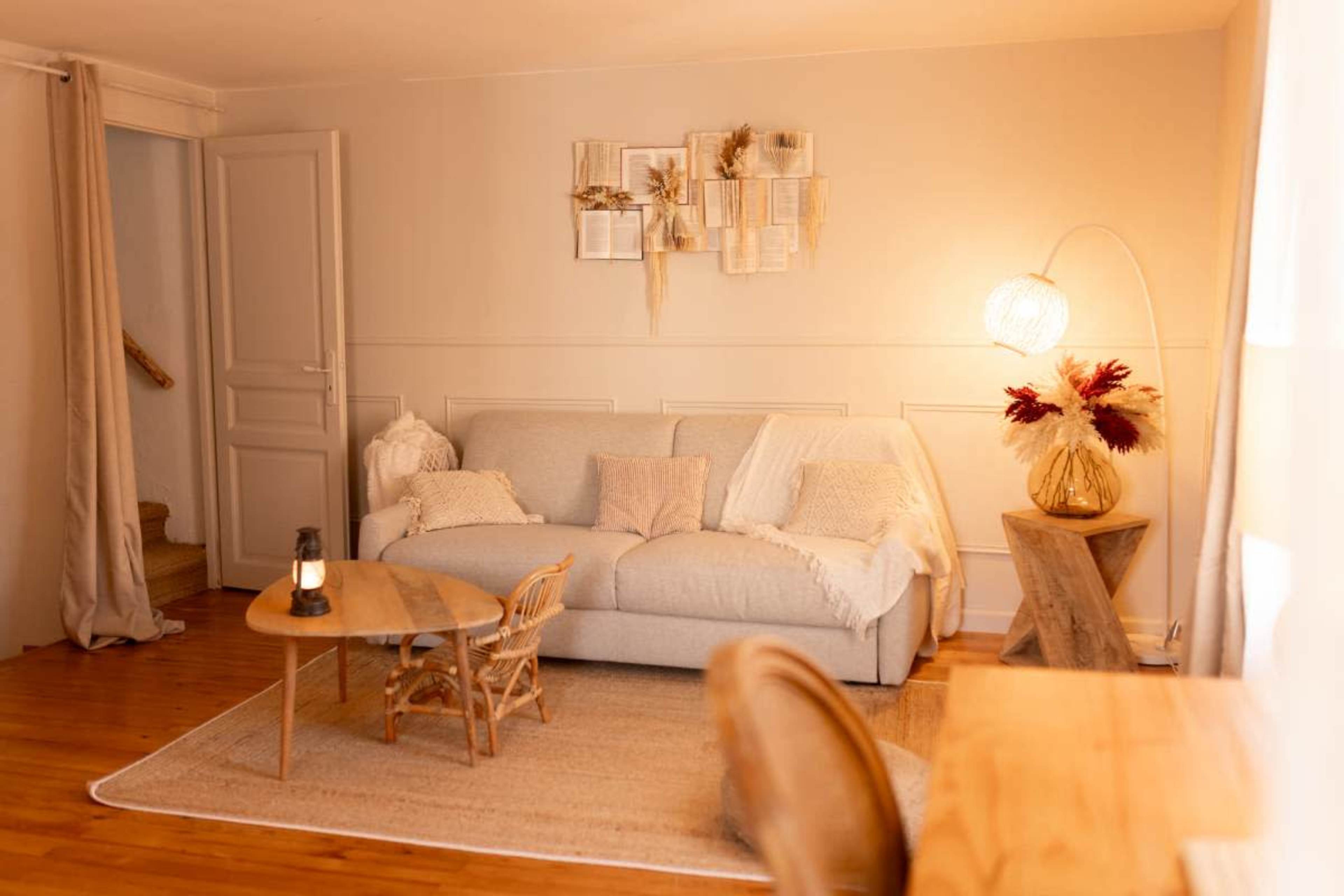 The image shows a cozy living room featuring a light-colored sofa, a small wooden coffee table, and decorative elements arranged thoughtfully.