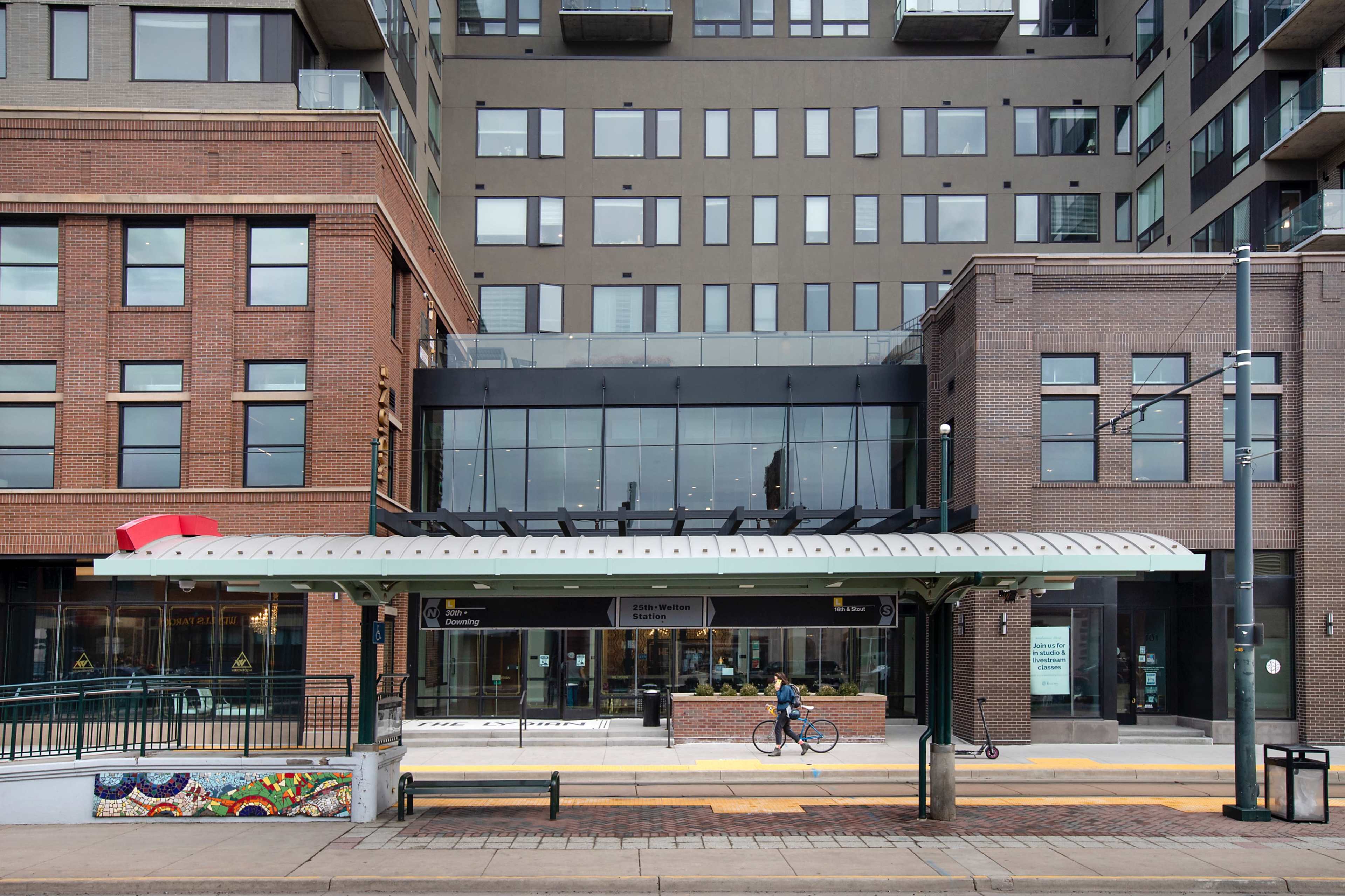 A modern building with a glass storefront and bike lane is situated alongside a bus shelter on a city street.