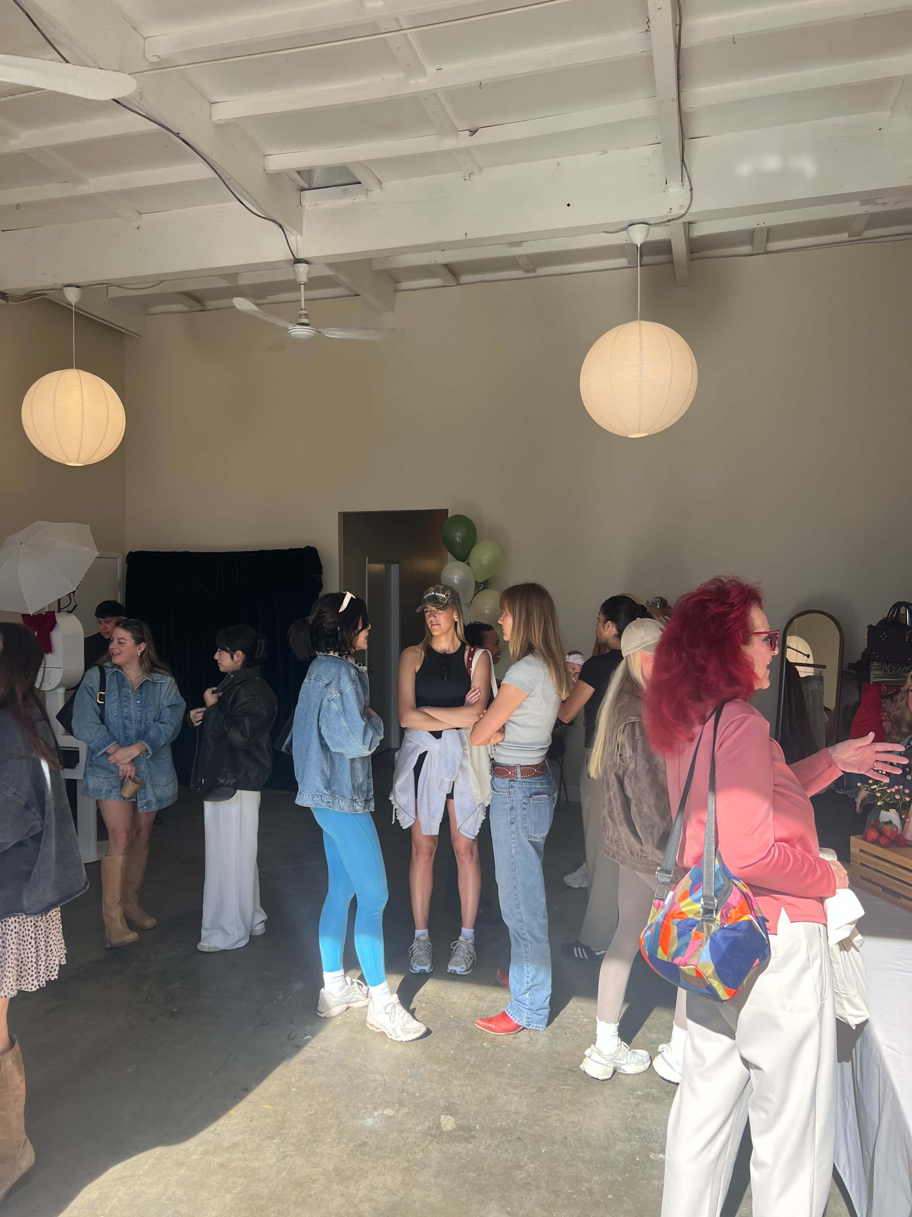 A group of people socialize in a brightly lit indoor space with pendant lighting and various decorations.