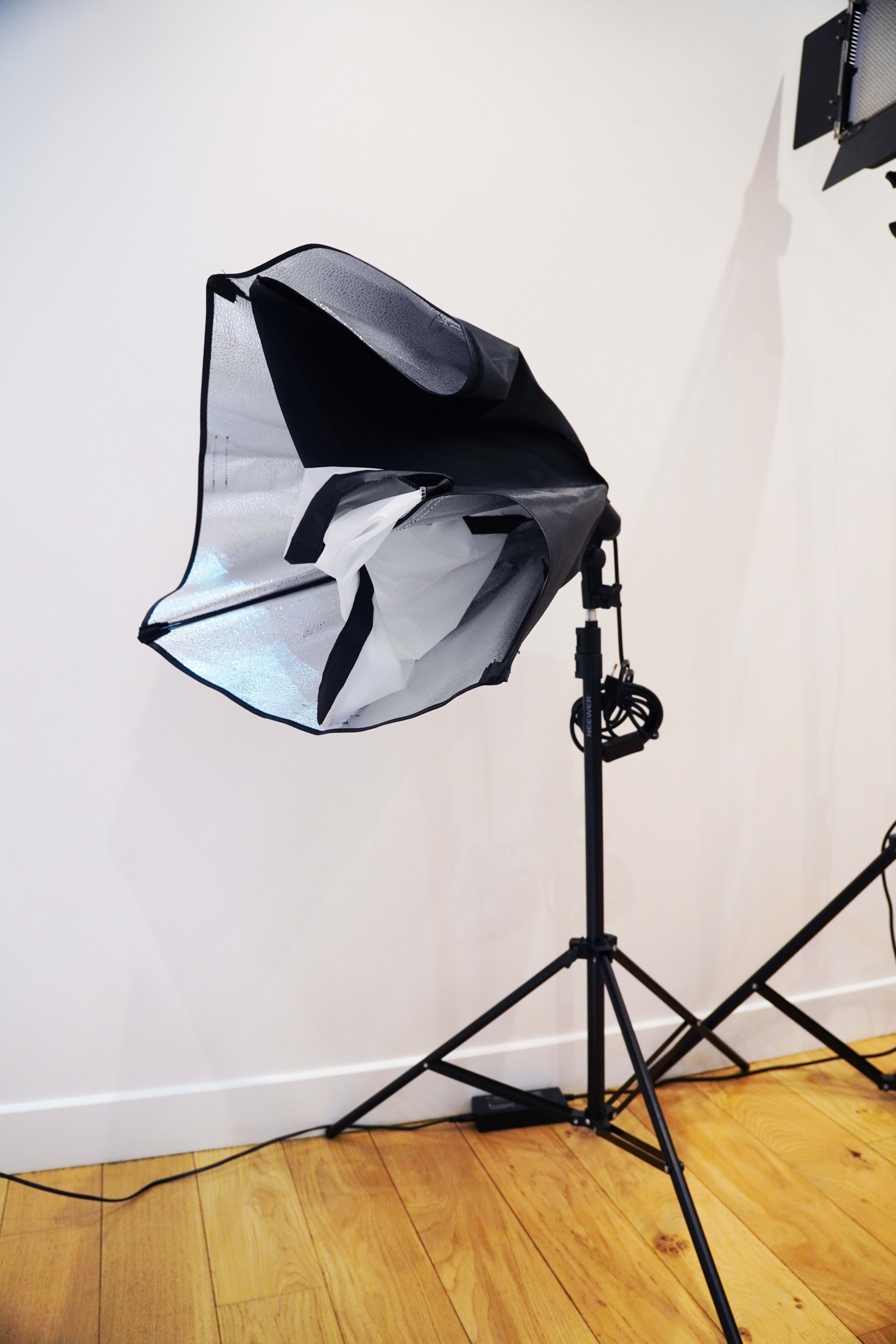 A light modifier on a stand is positioned against a wall with wooden flooring.