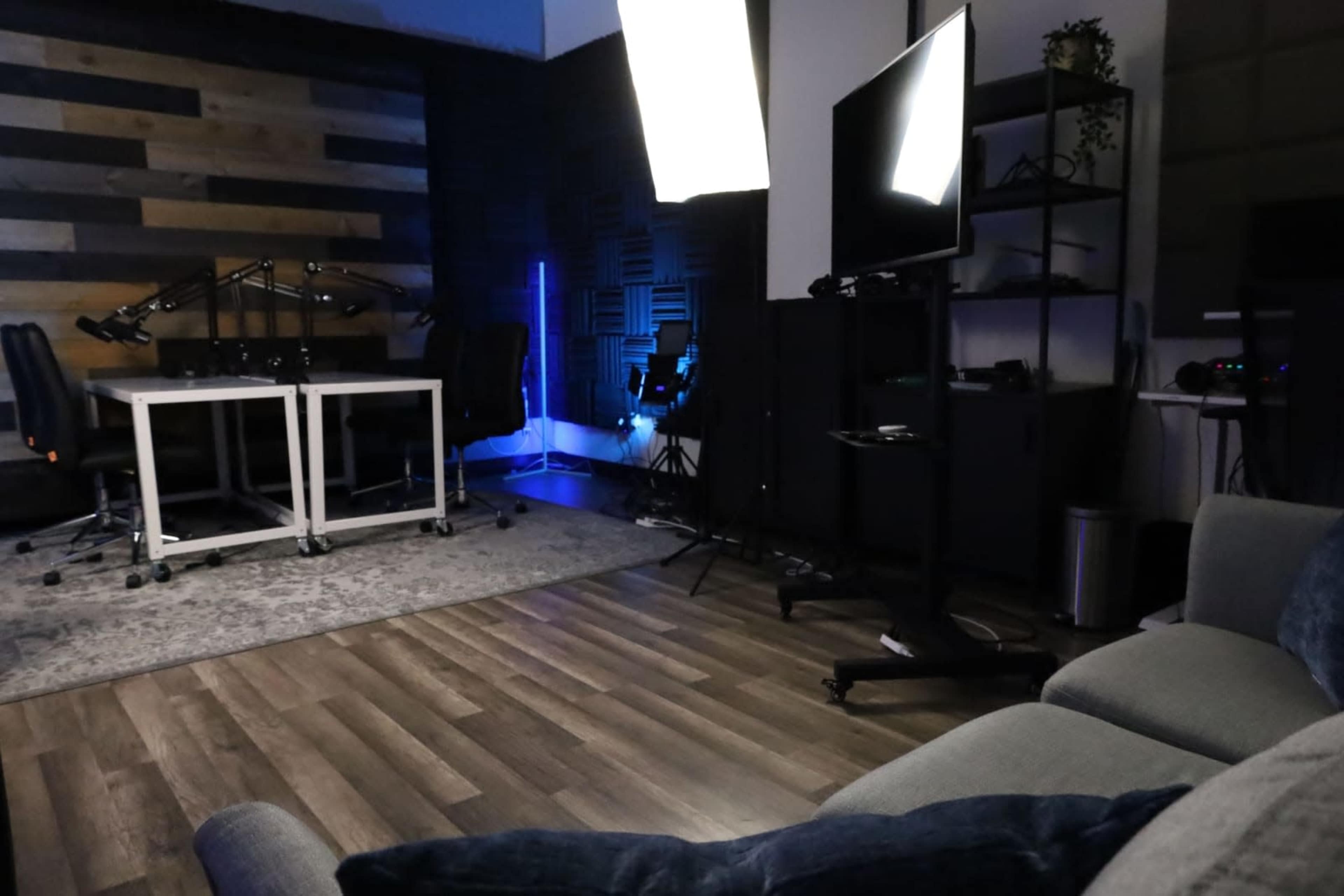 A modern studio space with two desks, professional lighting equipment, and a cozy seating area.