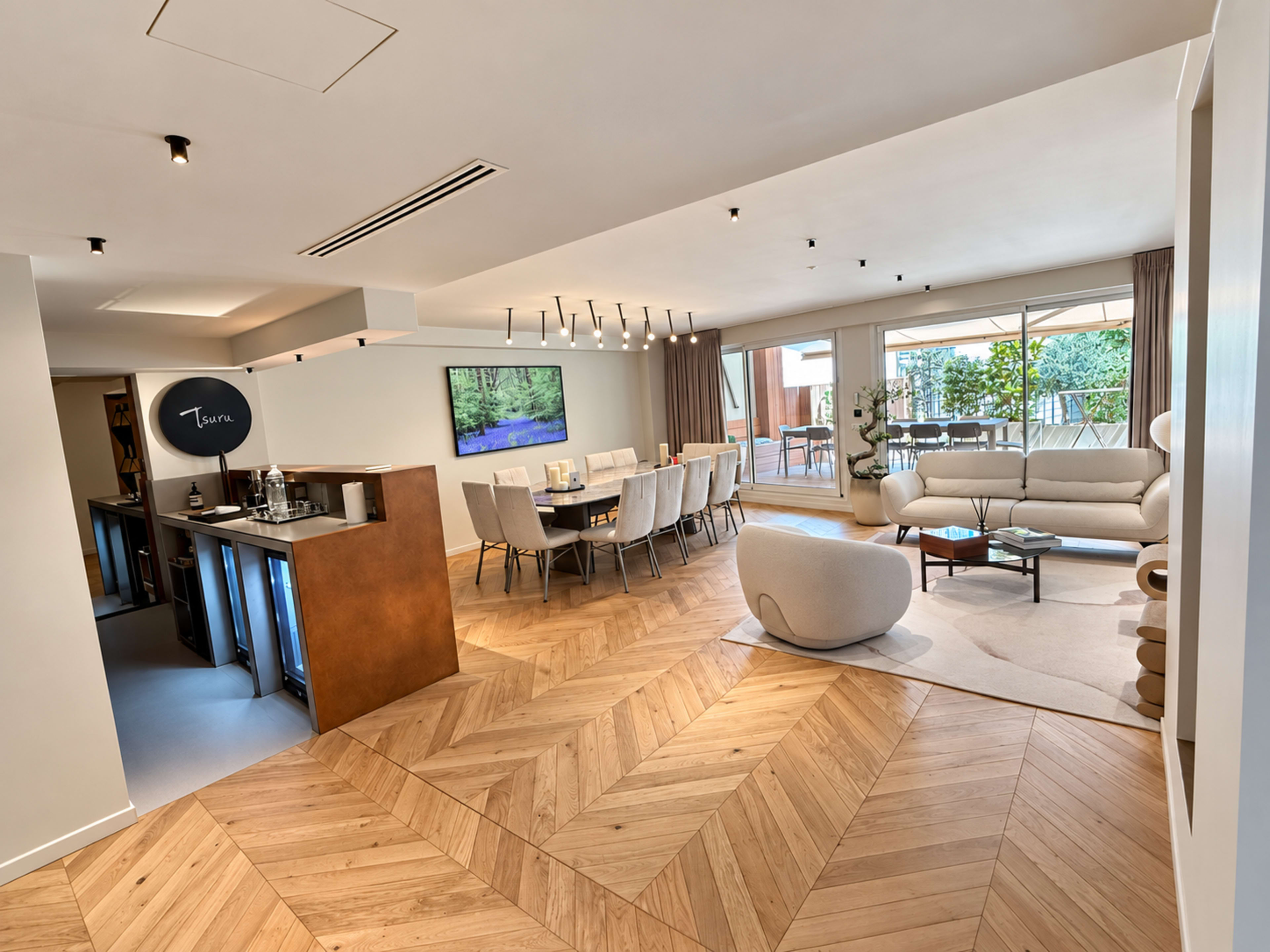 The image shows an elegantly designed open-plan living and dining area with modern furniture and large windows allowing natural light.
