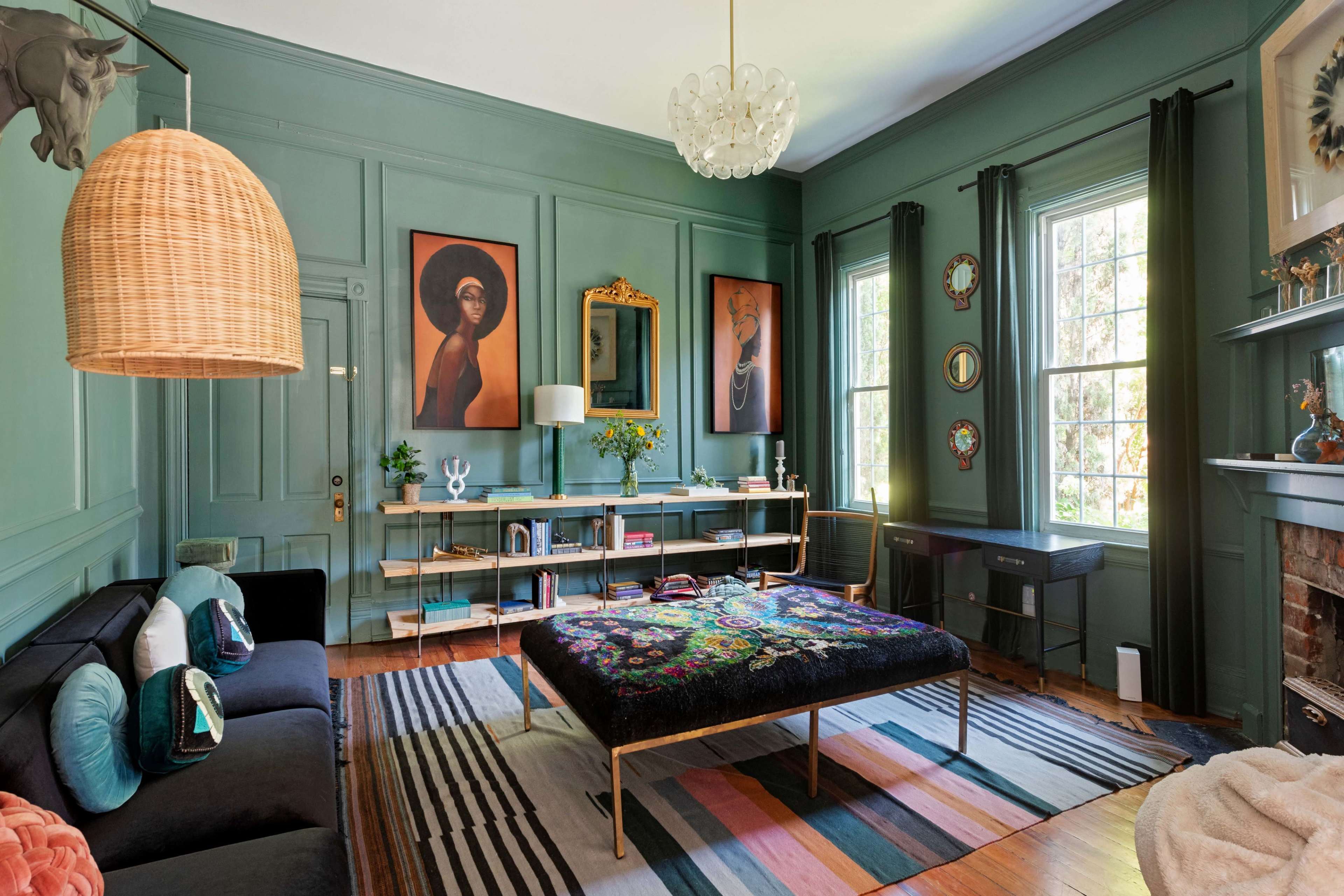 The image features a stylish living room with green walls, a large patterned coffee table in the center, and artwork displayed on the walls.