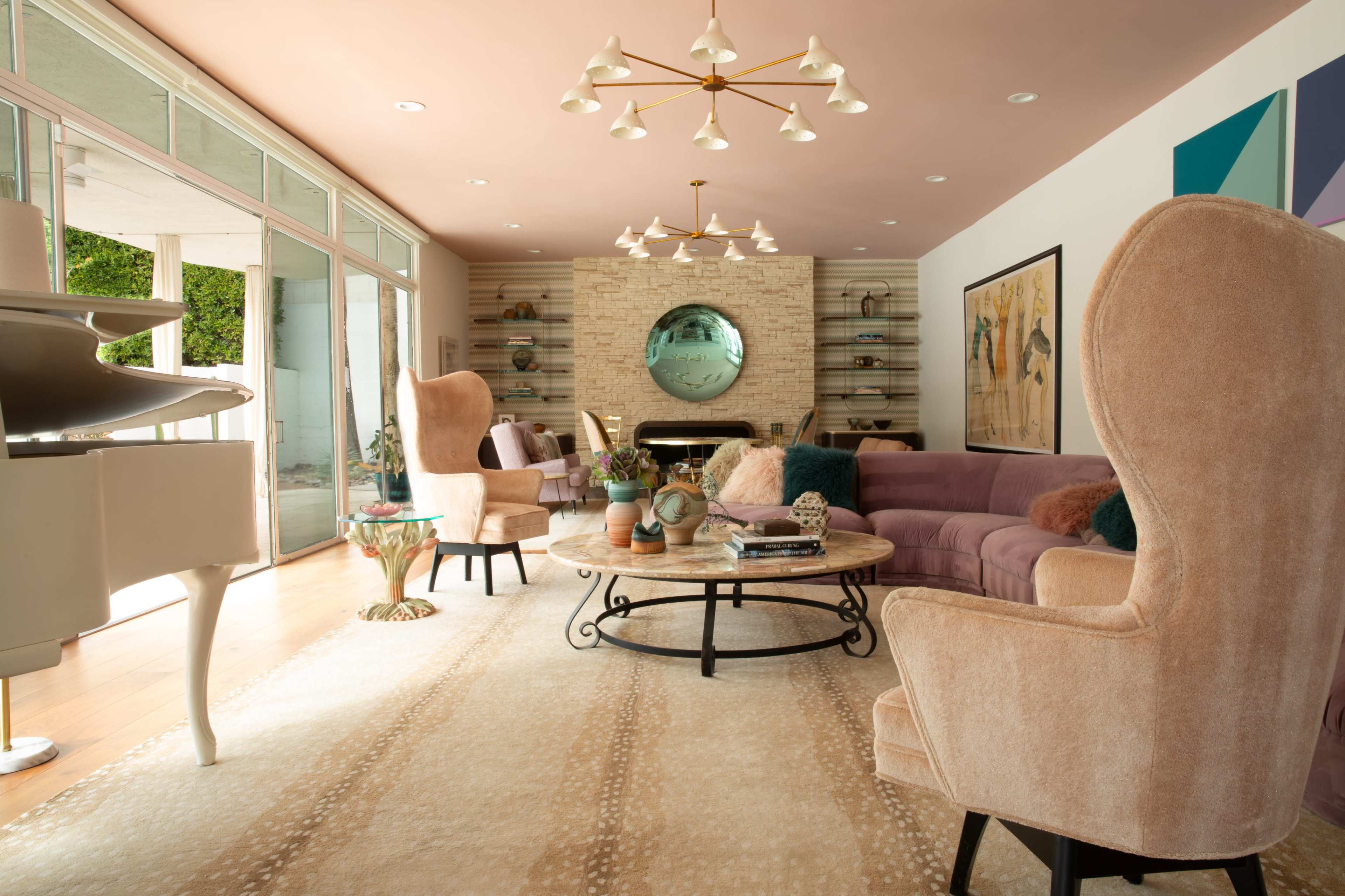 The living room features a light pink ceiling, a plush purple sofa, two cream-colored armchairs, and a round coffee table beneath a chandelier.
