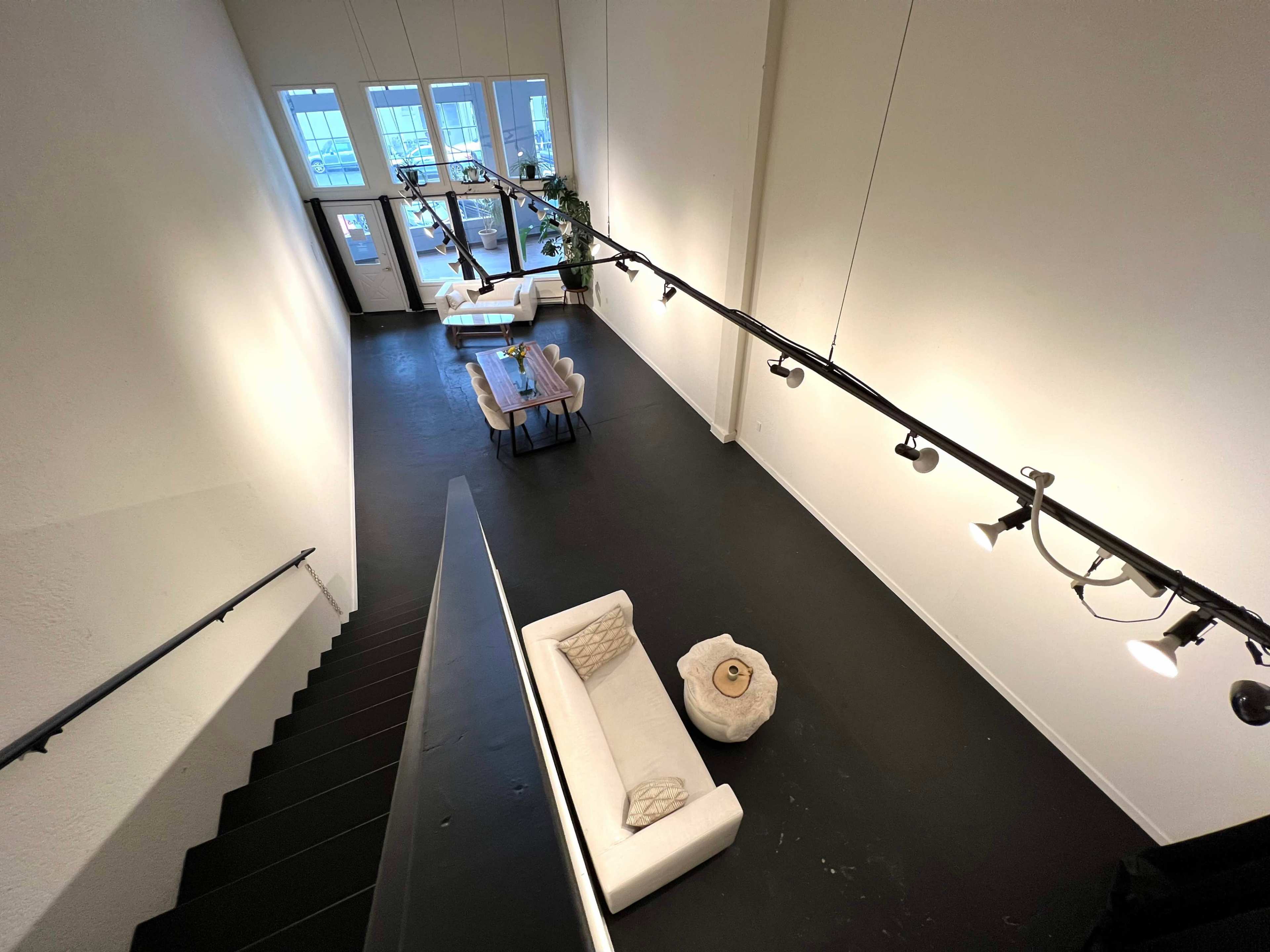 A spacious, well-lit room with a staircase leading down to a seating area and large windows that provide natural light.