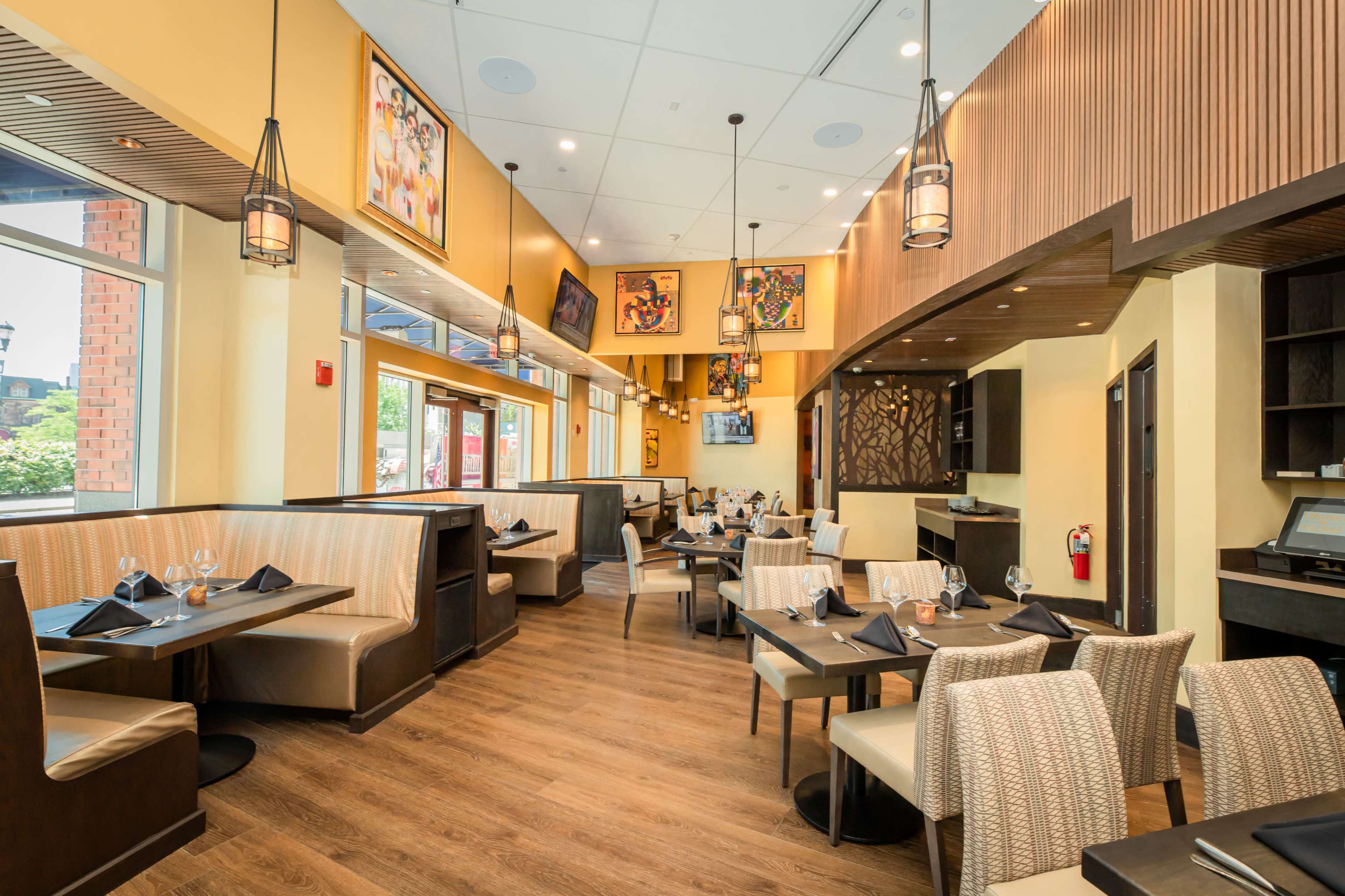 An interior view of a restaurant featuring booth seating, wooden floors, and decorative wall art.