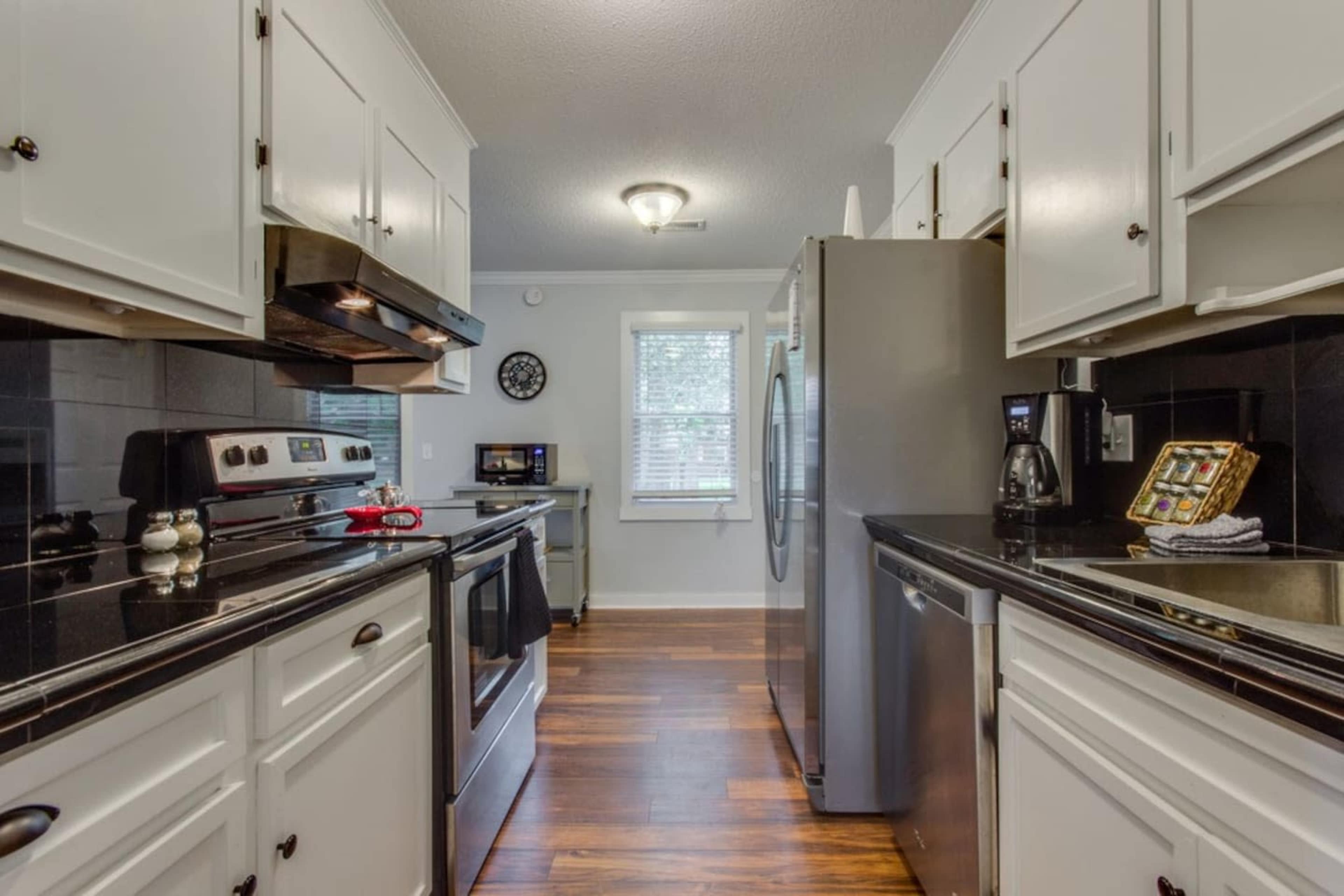 A modern kitchen with white cabinets, stainless steel appliances, and dark countertops.