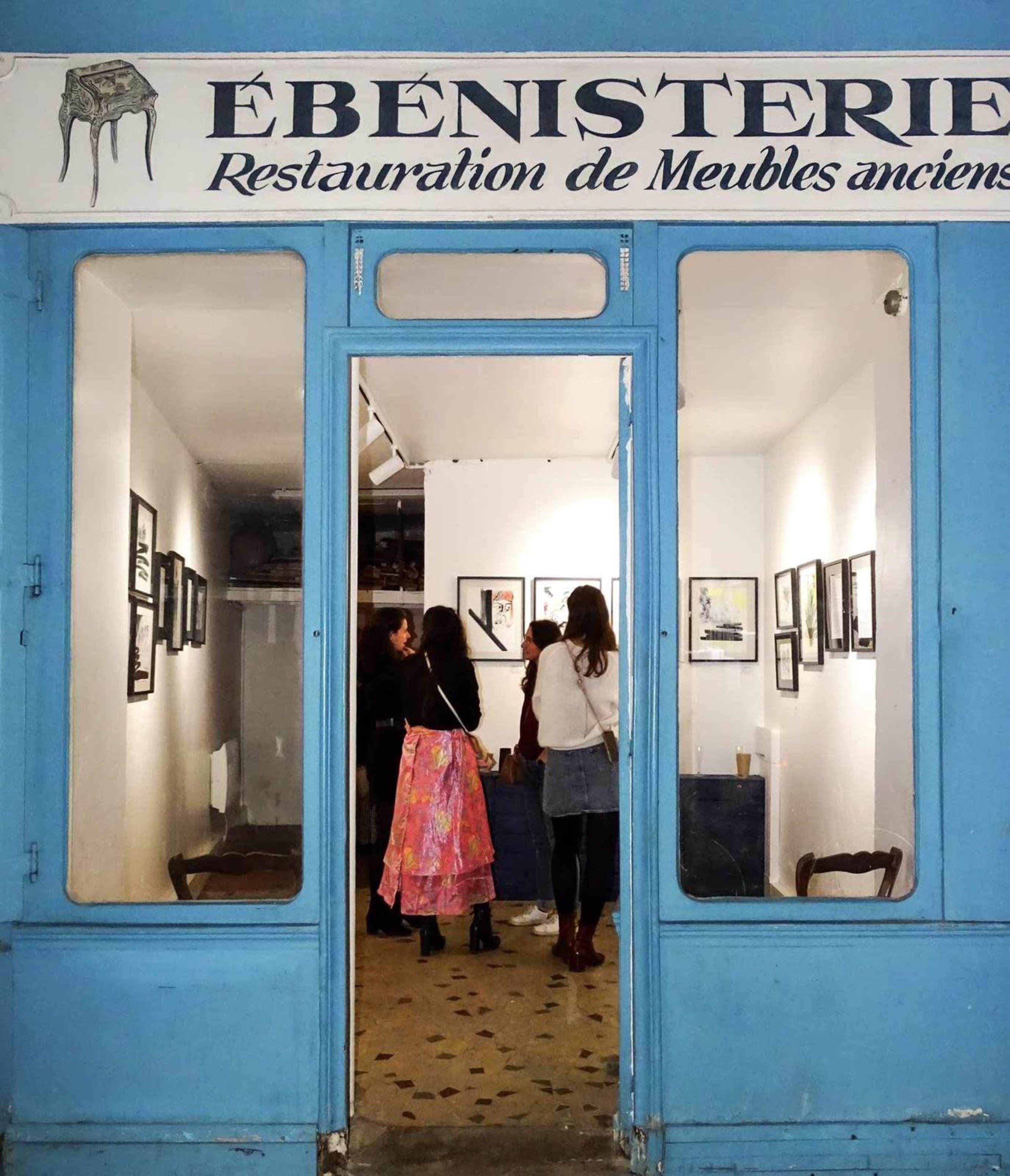 A storefront labeled "Ébénisterie" features an entrance leading to an interior with people admiring framed artwork on the walls.
