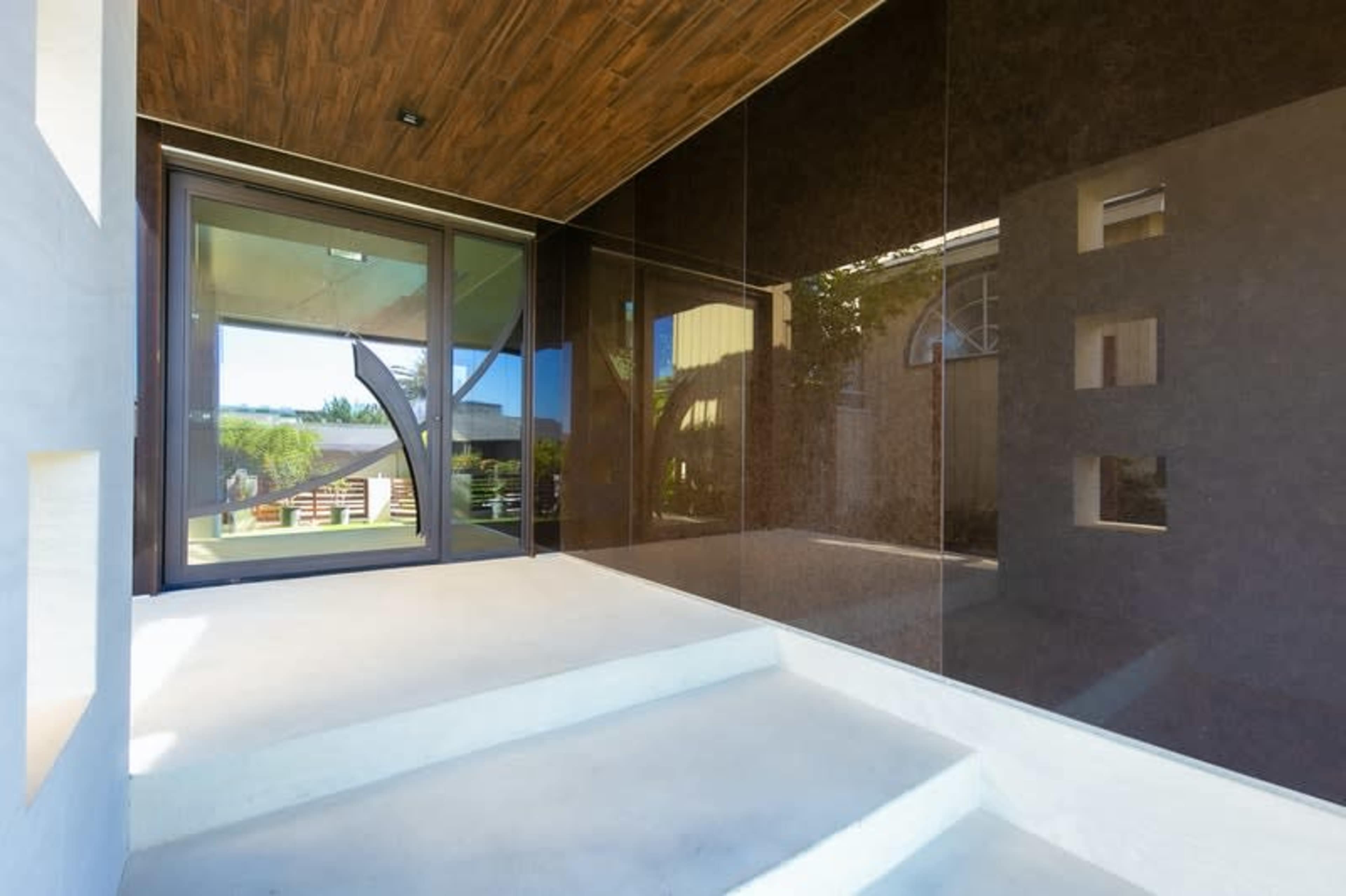 An entrance with a modern design featuring a glass door set against dark paneling and light concrete steps.