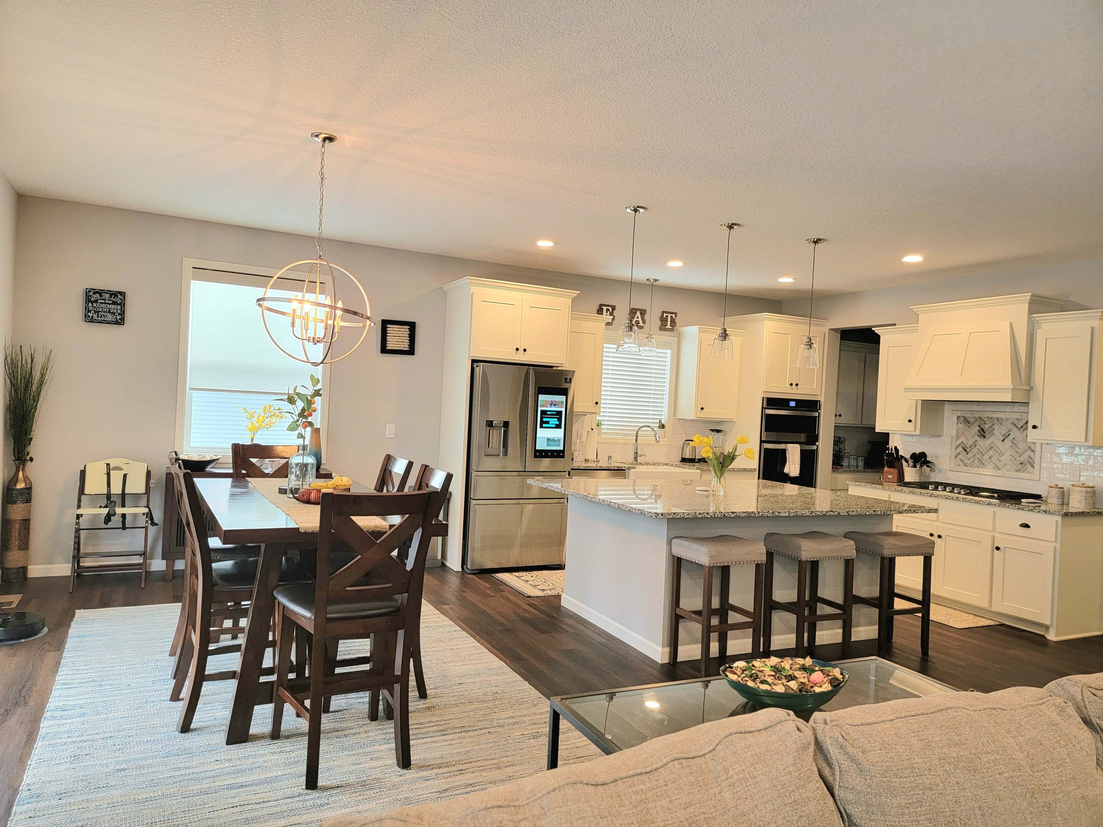 A modern kitchen and dining area with a large island, wooden dining table, and contemporary appliances.