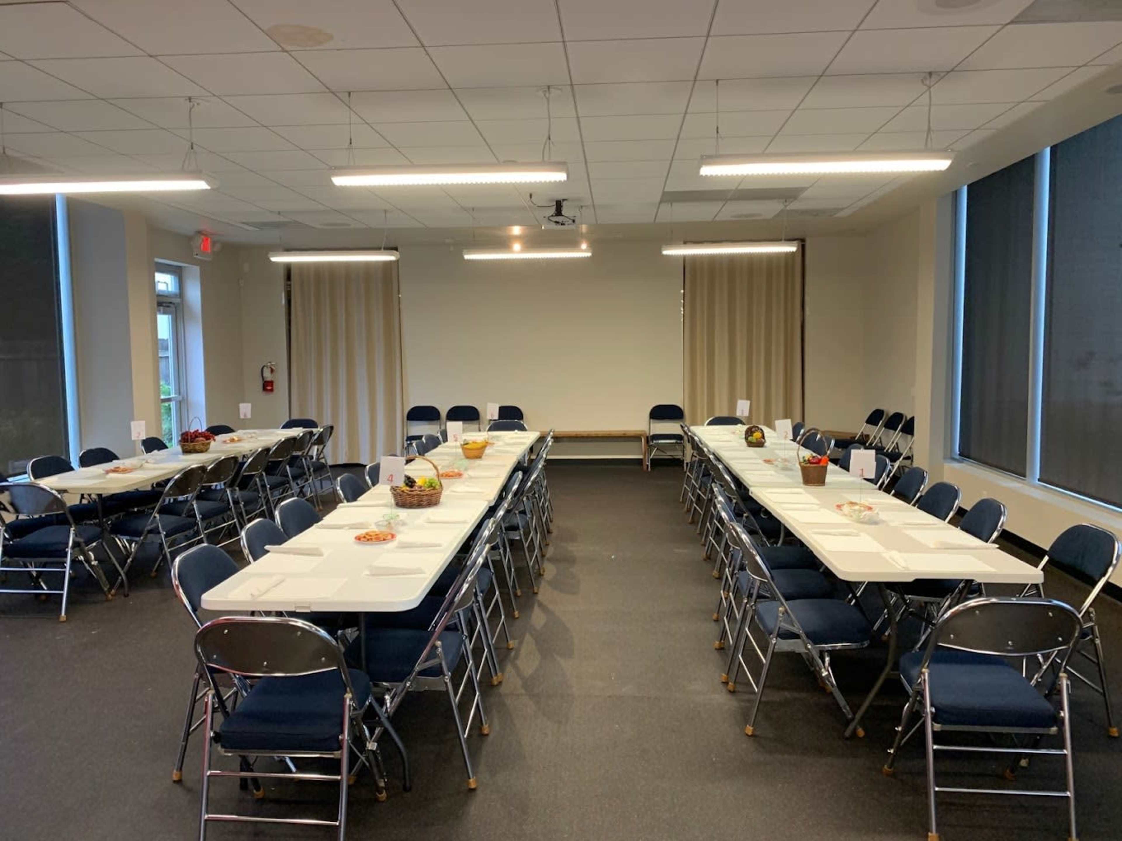A meeting room is arranged with several tables and chairs, set up for an event.