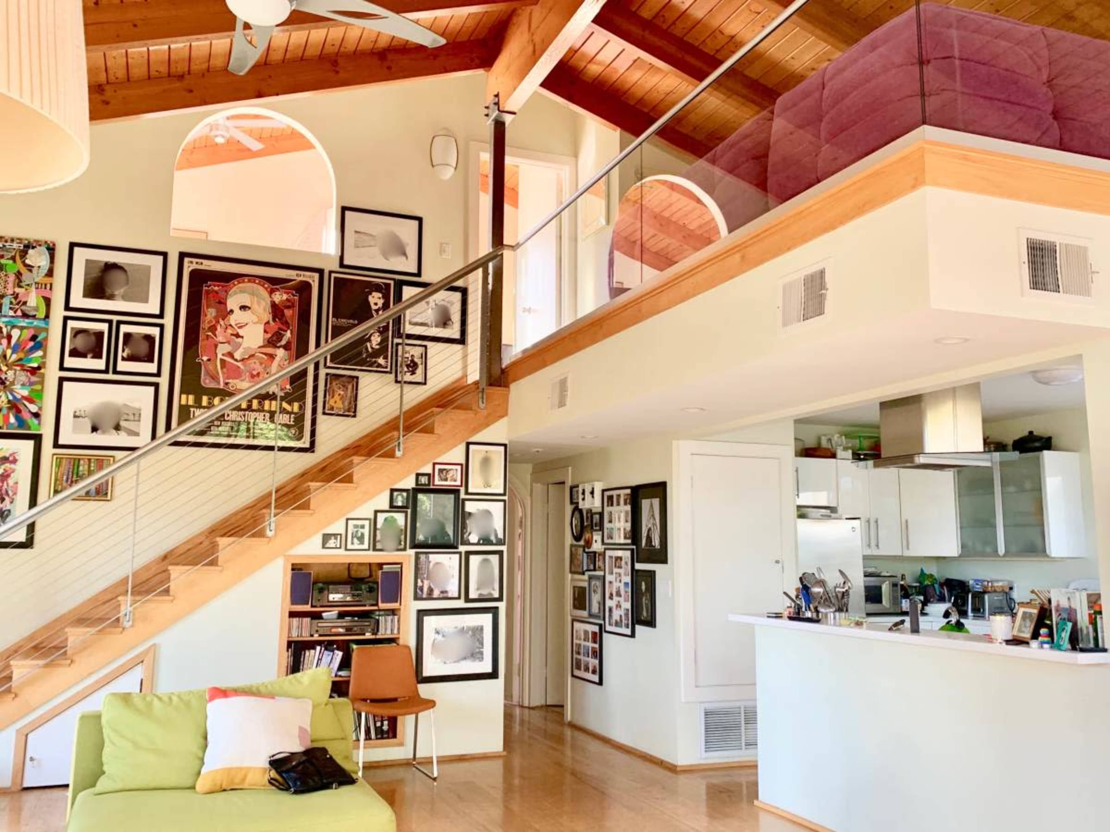 A modern interior features a staircase leading to an upper level, with walls adorned by a variety of framed artwork and photographs.