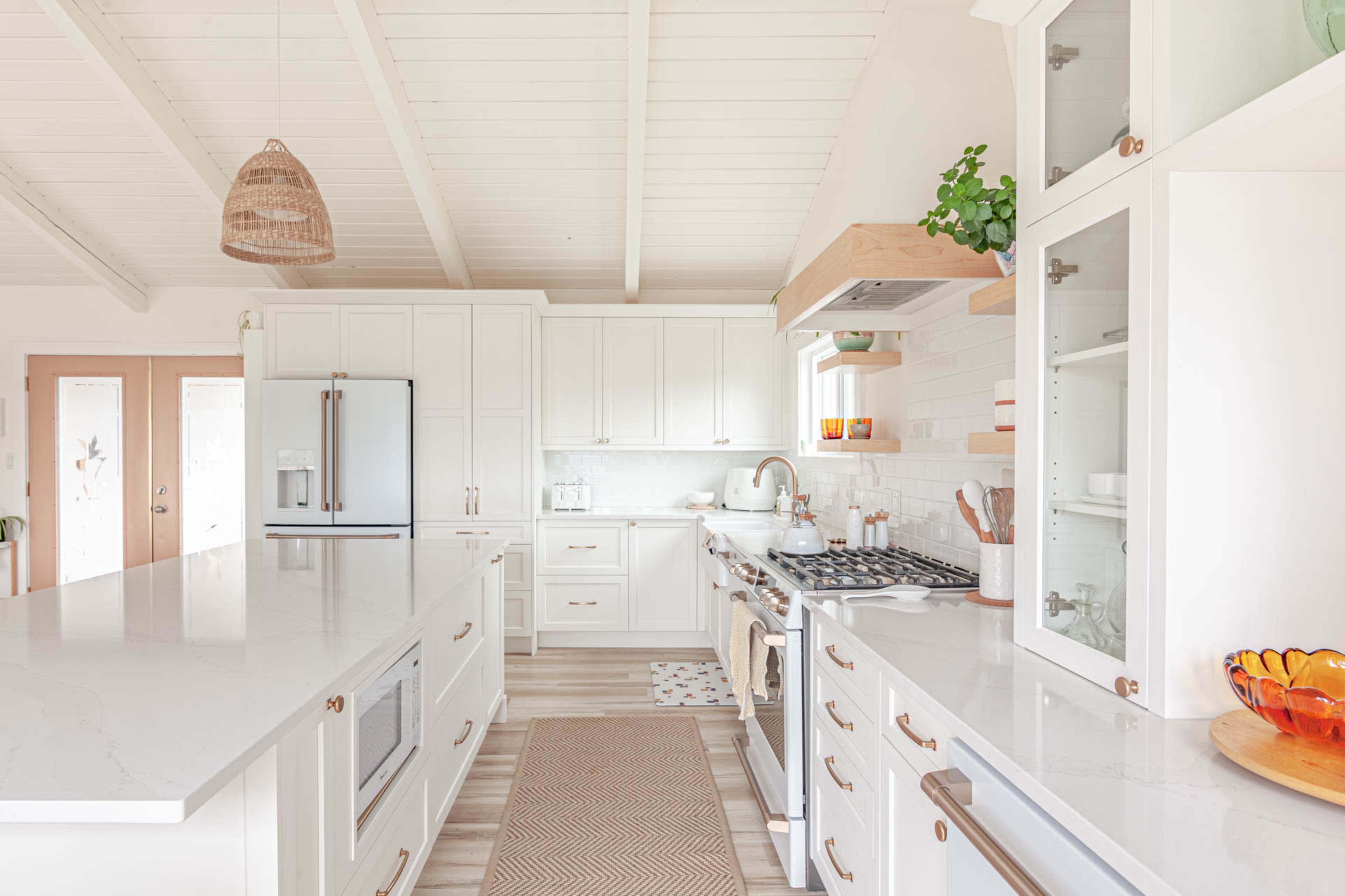 A modern kitchen features white cabinetry, stainless steel appliances, and a large island with a light-colored countertop.