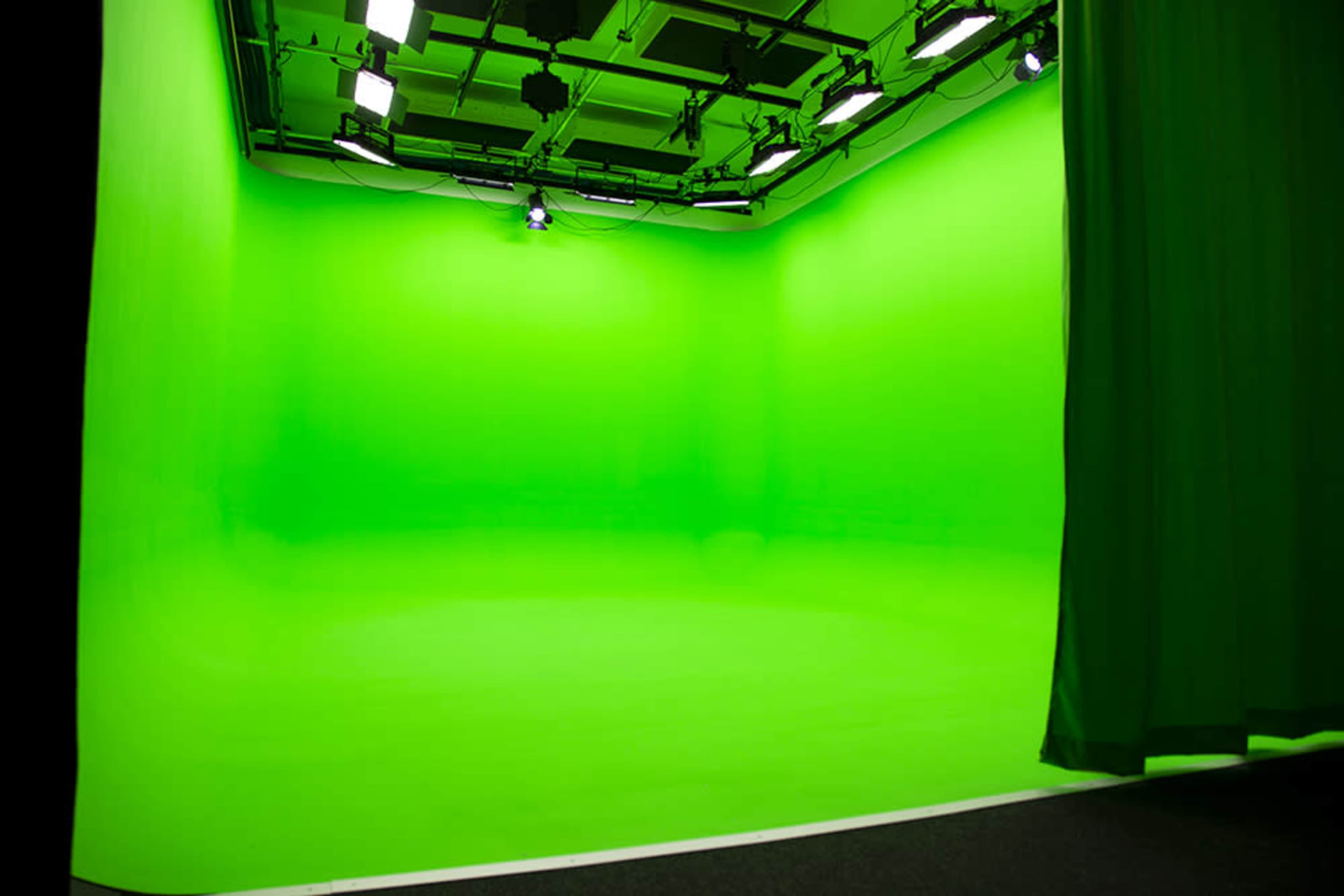 A green screen studio with a smooth, brightly lit backdrop and overhead lighting.